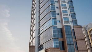 A modern high-rise building with a glass facade and a mix of rectangular and square windows. - Hotel Grand Central (Sihui)