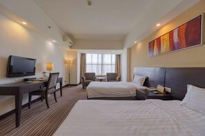 A hotel room with two beds, a desk with a chair, a television, and a window with curtains. - Hotel Grand Central (Sihui)