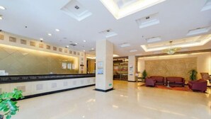 A hotel lobby with a reception desk, seating area, and a large mirror wall. - Hotel Grand Central (Sihui)