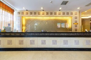A hotel reception area with a marble counter, a glass partition, and a bulletin board. - Hotel Grand Central (Sihui)