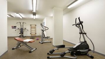 A fitness room with various exercise equipment, including a stationary bike, elliptical, and weight machine.