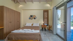 A bedroom with a bed, wooden wardrobe, and a wall-mounted decorative item. - Gyri Villa, overlooking Vassiliki bay (Lefkada)