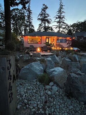 A house with a fire pit, outdoor seating, and a view of the surrounding forest.