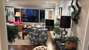 A living room with a wooden dining table, sofas, a TV, and decorative items.