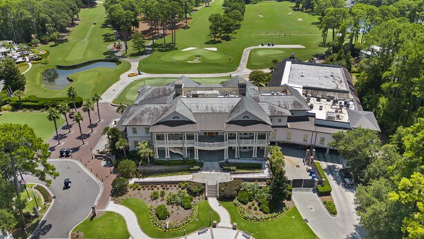 A golf course with a clubhouse featuring a large central building with multiple stories and a covered patio area. - Awesome location 2 Bedroom Condo w/ Pool, walk to Beach, Park and Coligny Plaza! (Hilton Head Island)