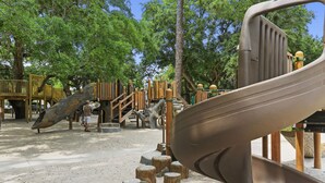 A playground with a slide, climbing structures, and wooden steps. - Awesome location 2 Bedroom Condo w/ Pool, walk to Beach, Park and Coligny Plaza! (Hilton Head Island)