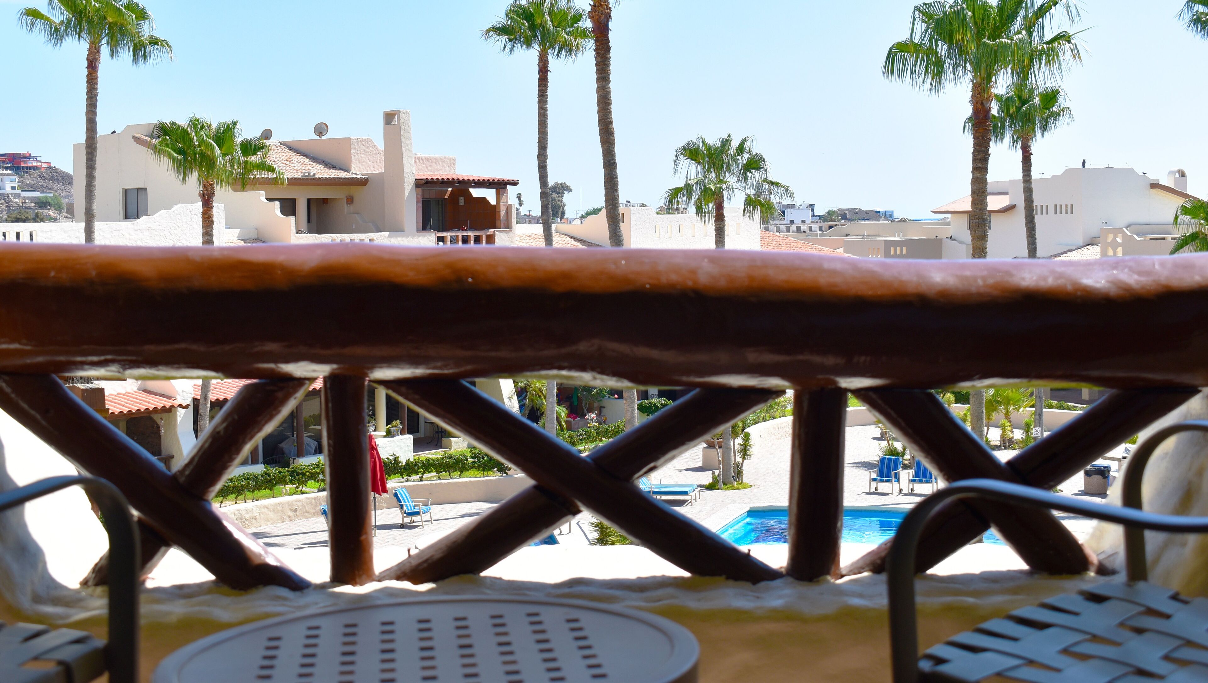 Blick auf einen Pool mit Palmen und Gebäuden im Hintergrund.
