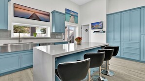 Una cocina moderna con una isla central, armarios azules y una zona de bar con taburetes.