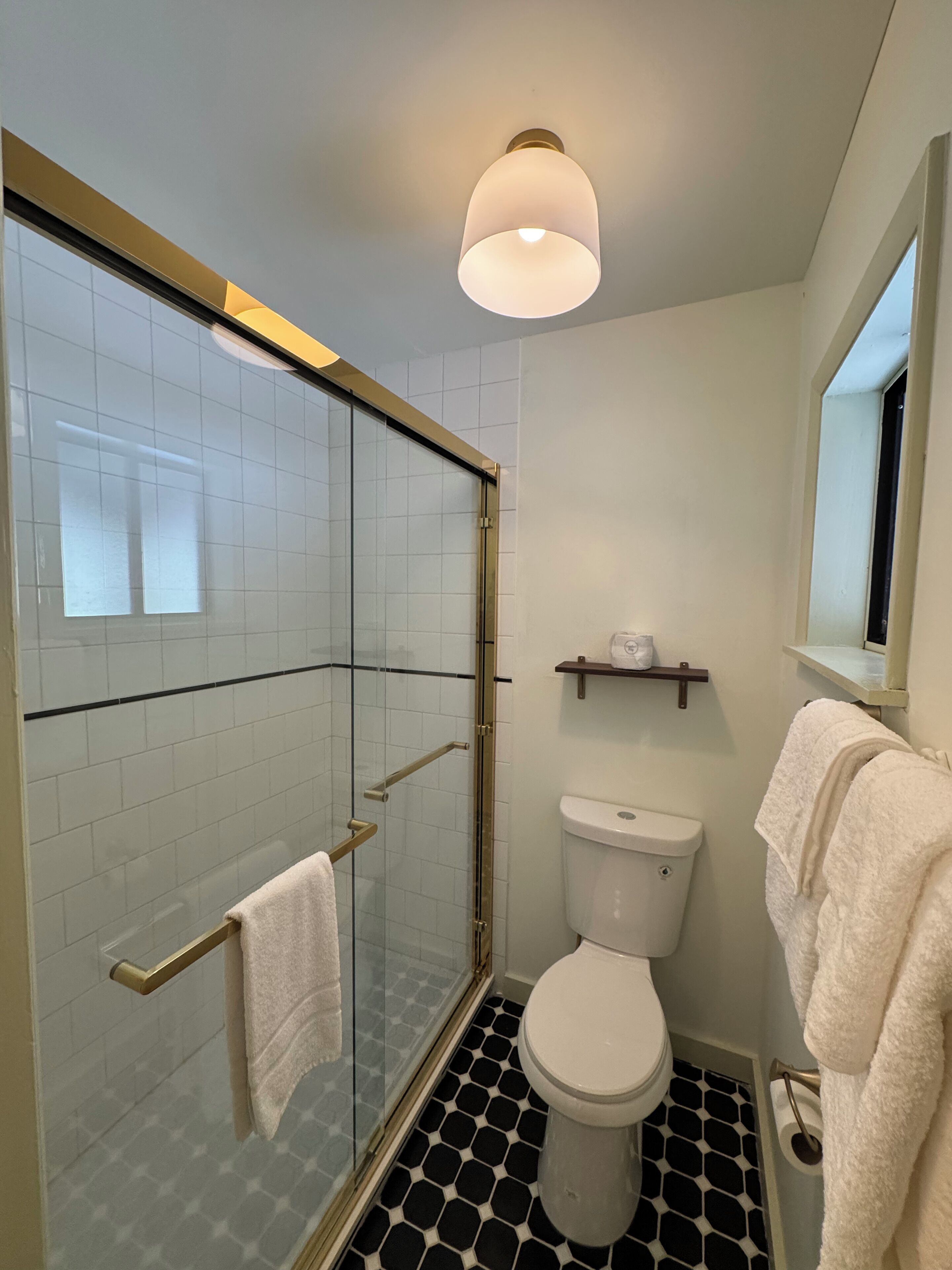 Ein Badezimmer mit einer Glasduschkabine, einer Toilette und einem Waschbecken.