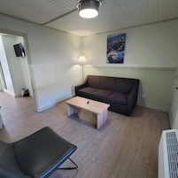 Una sala de estar con un sofá marrón, una mesa de centro de madera y una silla negra.