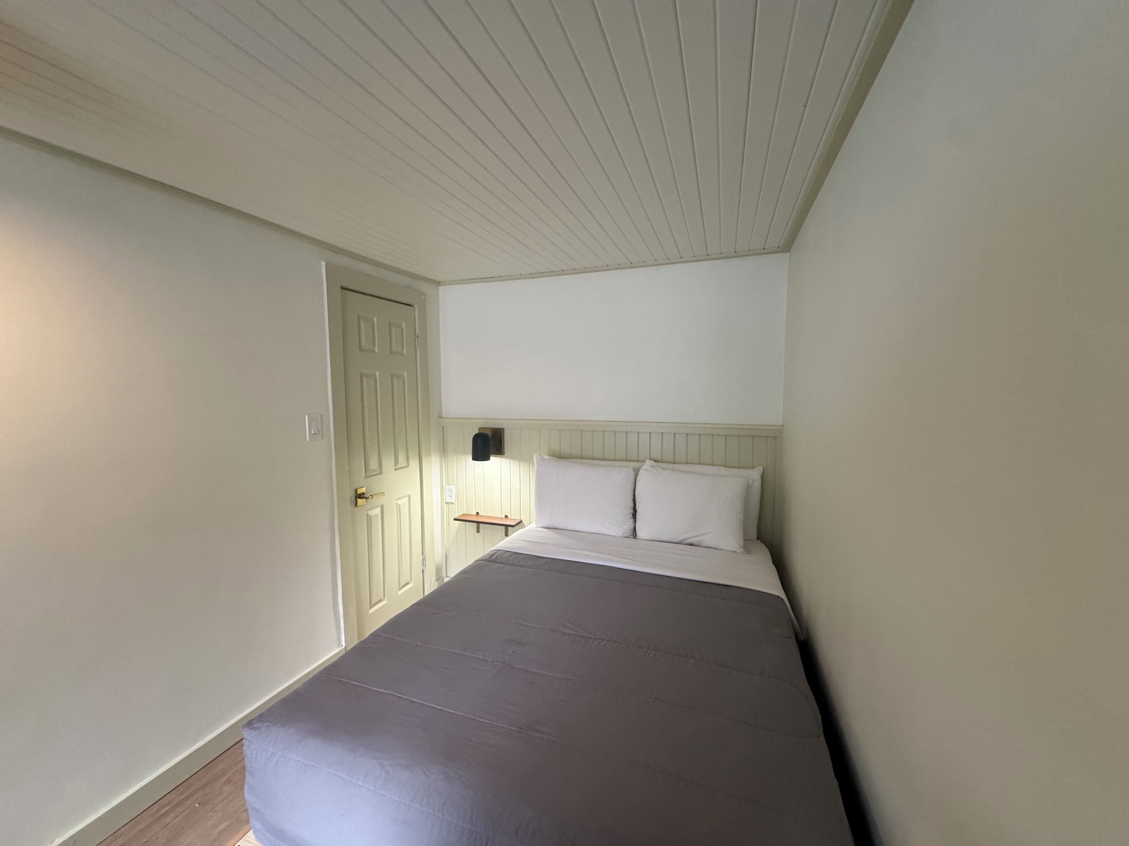 Un dormitorio con cama, mesita de noche y una puerta.