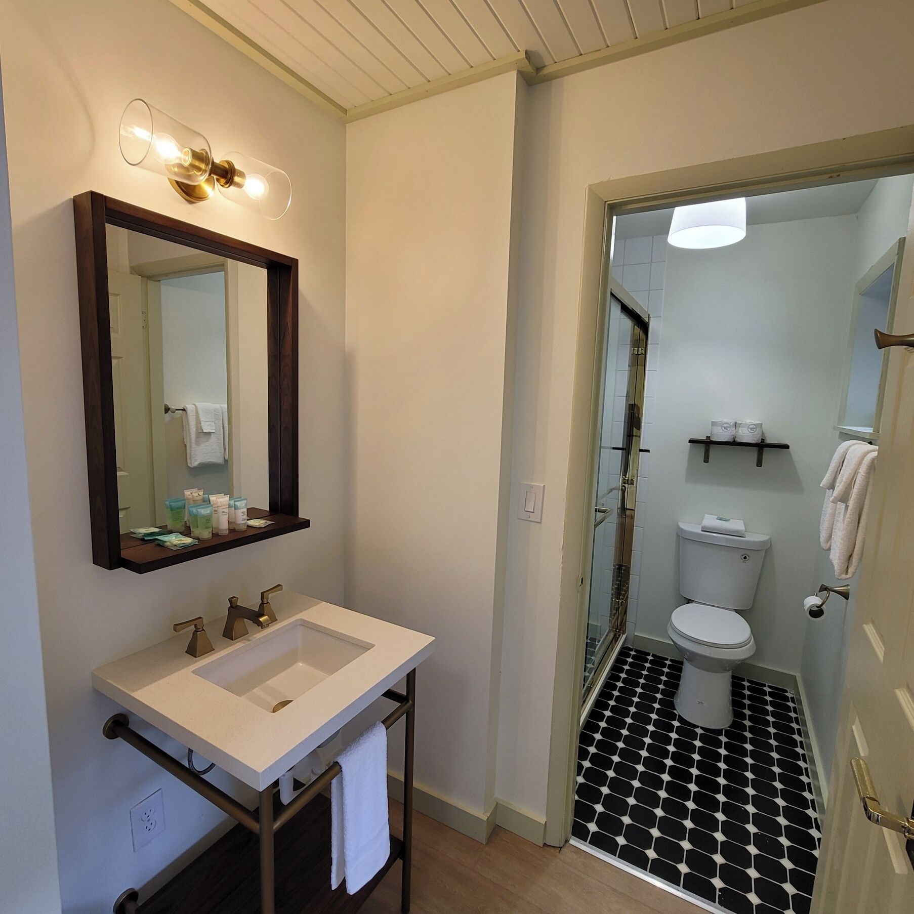 Un baño con un lavamanos blanco, un espejo y una zona de ducha.