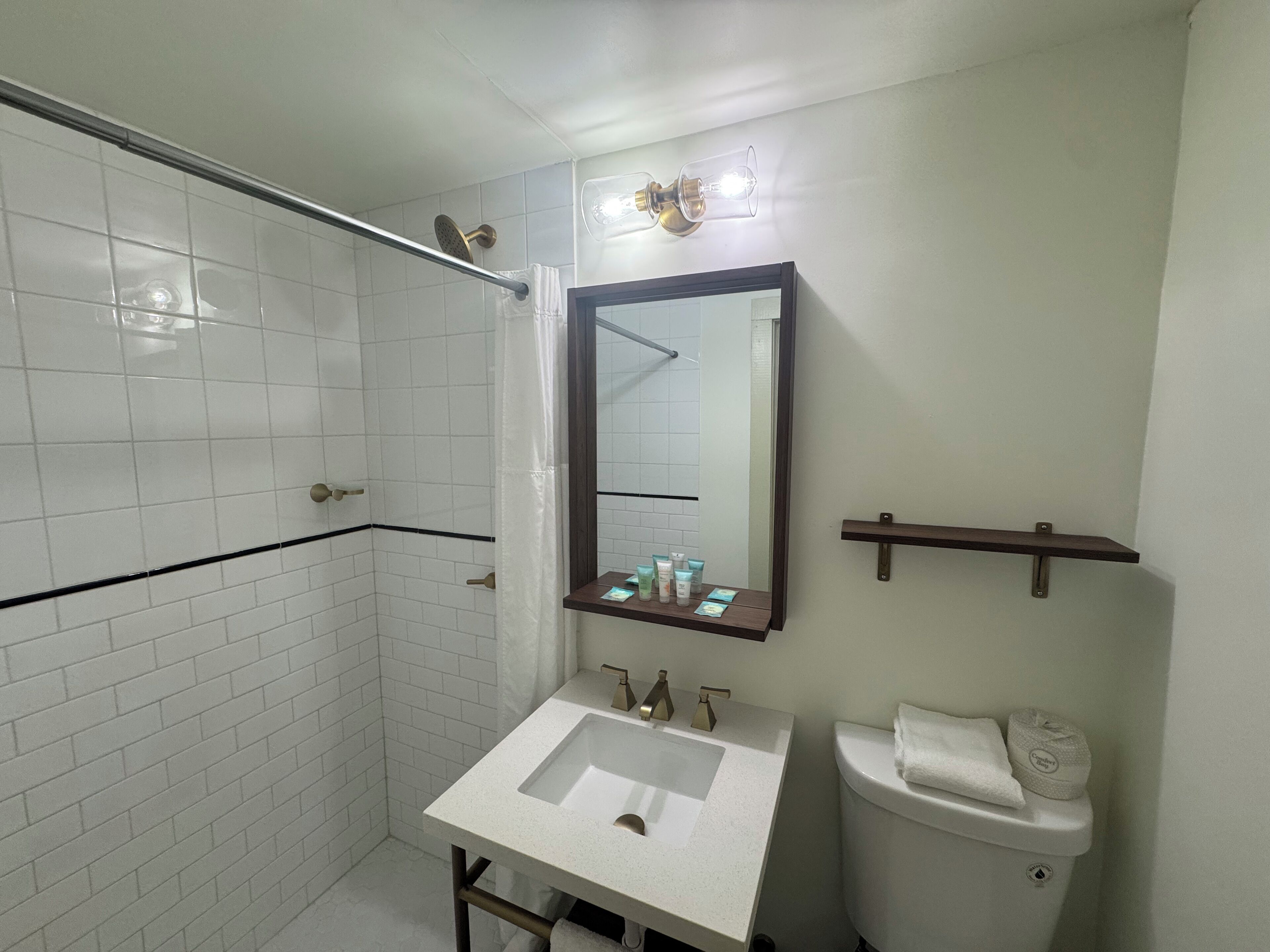 Un baño con un lavabo blanco, un espejo, un inodoro y una zona de ducha.