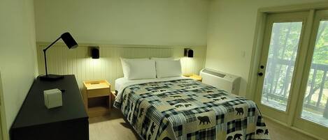 A bedroom with a bed, bedside tables, a desk, and a ceiling light.