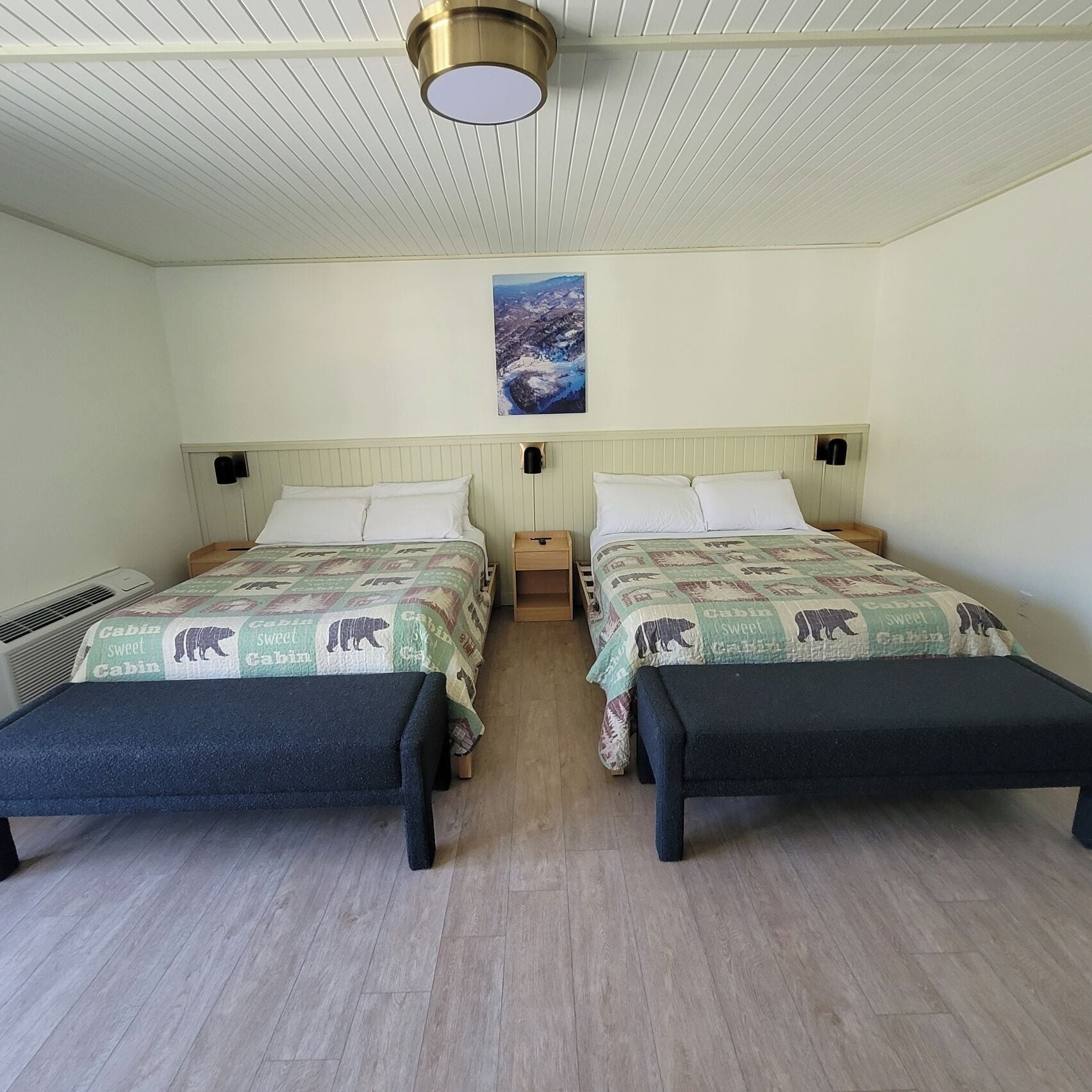 A twin bedroom with two beds, a ceiling fan, a mounted picture, and a window.