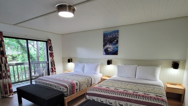 A bedroom with two beds, a large window, and a ceiling light. - Ski Mountain Lodge (Gatlinburg)