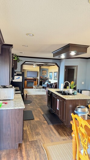 A spacious kitchen with a central island, wooden cabinets, and a dining area with a view. - Lakefront Gem for Family/Fishermen Getaway - 1 Hour from Dallas (Bonham)