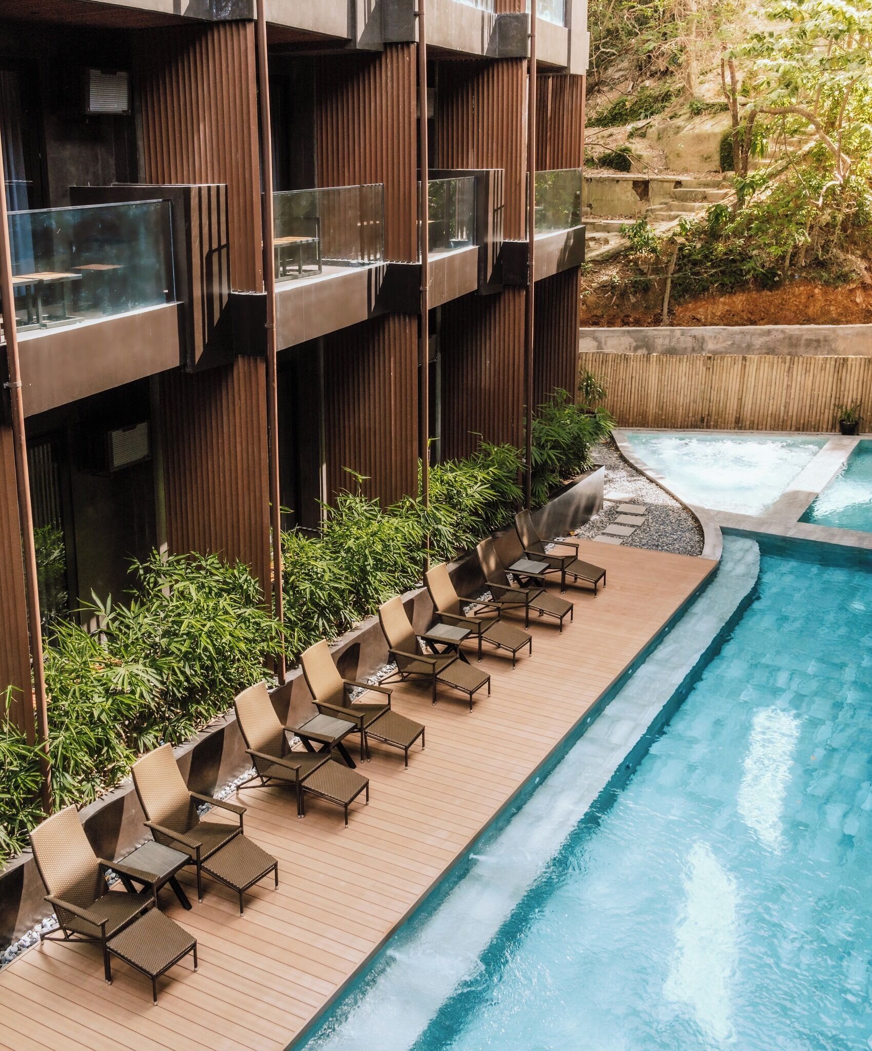 Un área de piscina en la azotea con sillones de descanso y un jacuzzi.