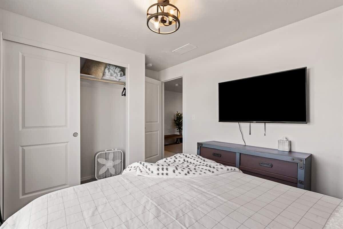Een slaapkamer met een bed, een dressoir, een televisie en een inloopkast.