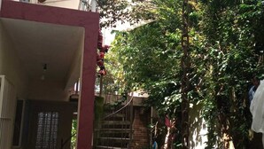 A narrow courtyard with a wooden floor, a red structure on the left, and a staircase leading to an upper level. - Spacious suites near Tabatinga Beach (Ubatuba)
