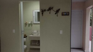 A bedroom with a bed, a bathroom with a sink, and a mirror. - Spacious suites near Tabatinga Beach (Ubatuba)