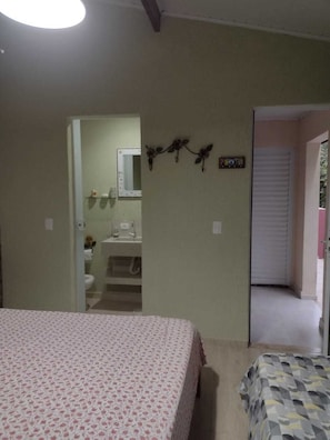 Quarto com cama, banheiro com pia e espelho.