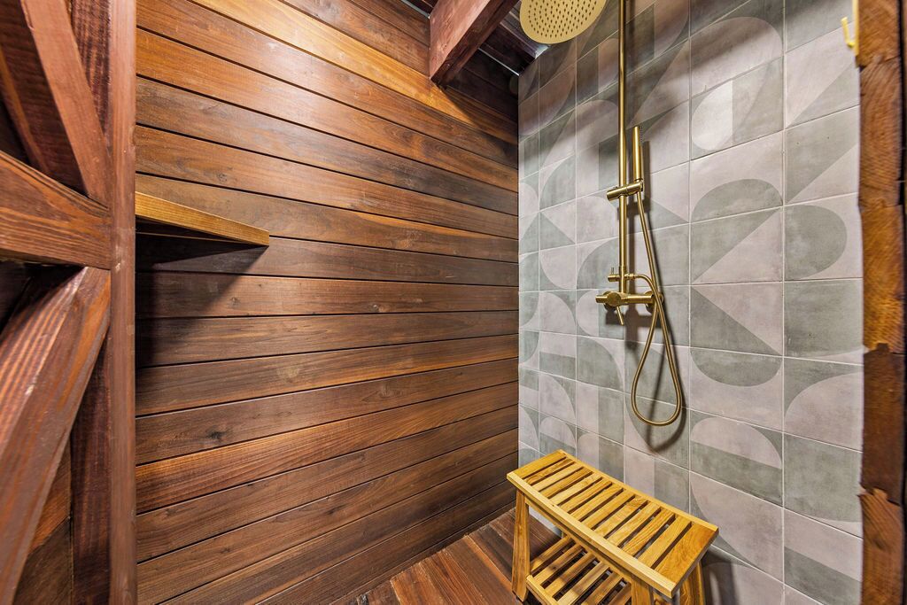 Een houten interieur met een douchegedeelte, inclusief een bankje en douchekop.