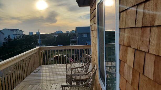 A wooden deck with wicker chairs and a glass railing overlooking a residential area. - 500 feet to the Beach, Full house with Stocked Kitchen, Linens & Beach Supplies (Avon)