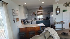 A modern kitchen with a central island, bar stools, and a dining area with a sofa. - 500 feet to the Beach, Full house with Stocked Kitchen, Linens & Beach Supplies (Avon)