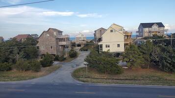 A coastal road with houses on both sides, a clear sky, and a view of the sea.