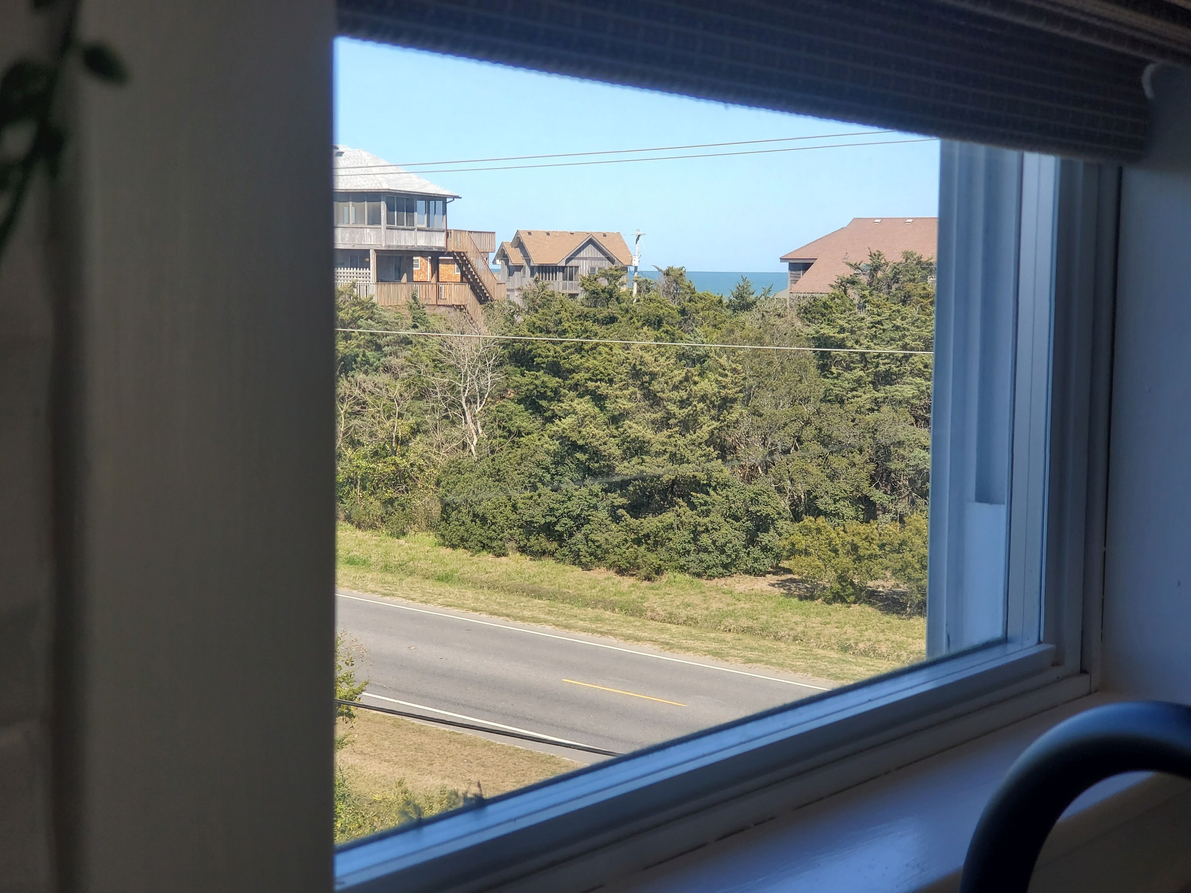 Une vue par la fenêtre sur une route bordée de maisons et d’arbres.