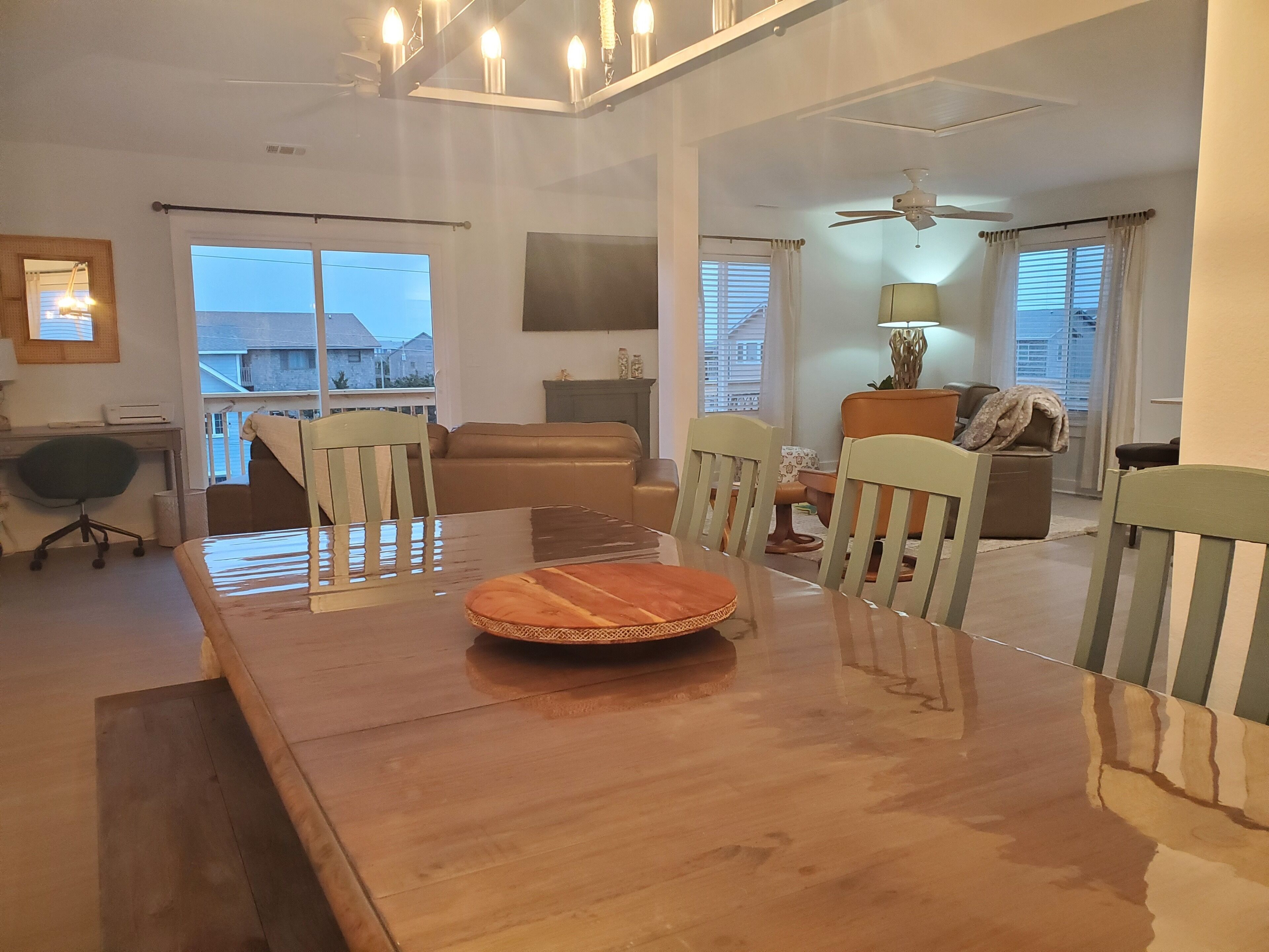 Un vaste espace dédié à la salle à manger, avec une table et des chaises en bois, un ventilateur de plafond et une vue sur l’extérieur.