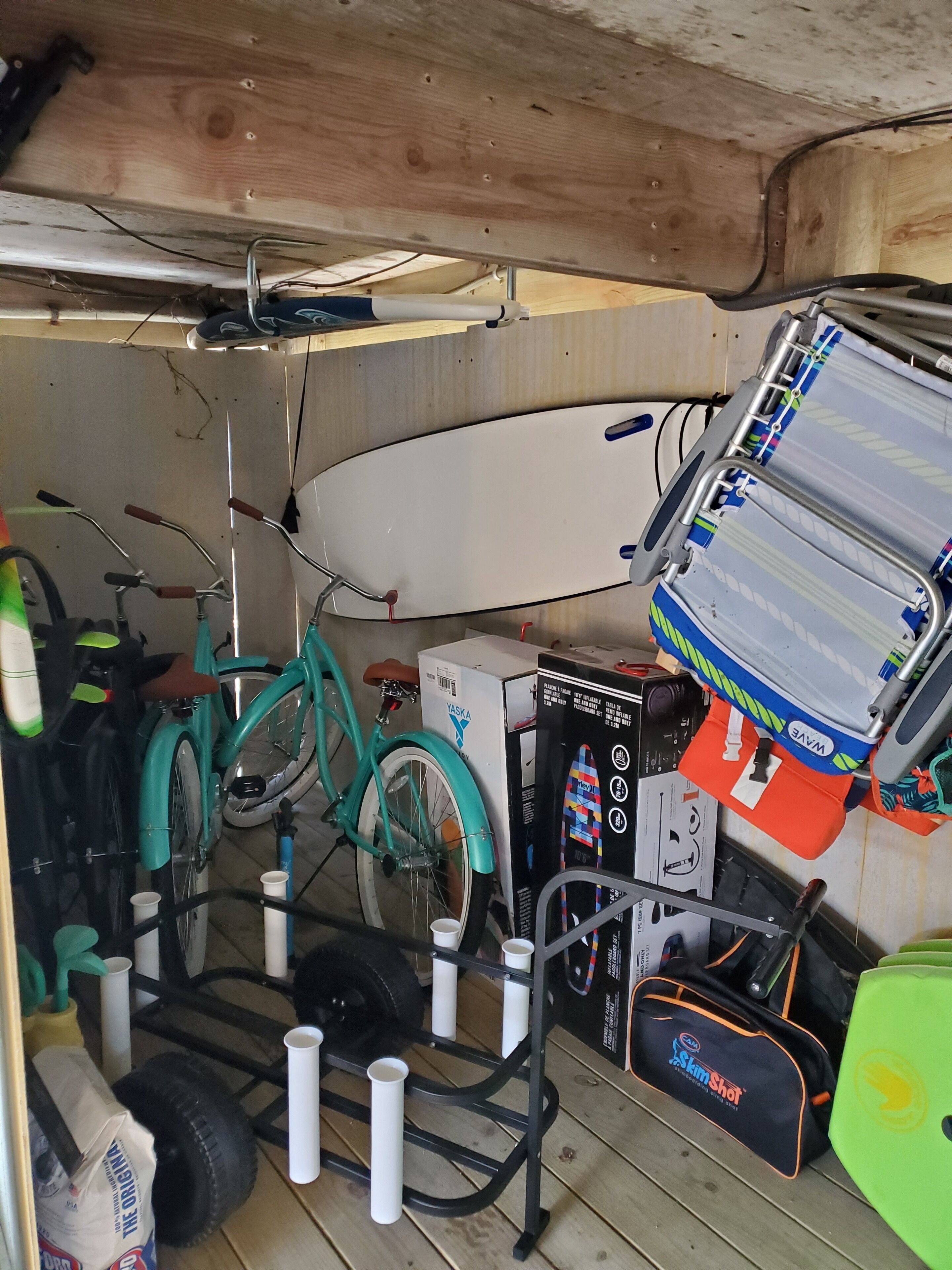 Un espacio de almacenamiento con una bicicleta, una tabla de surf y varias bolsas y equipo.