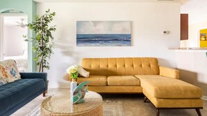 Ein Wohnzimmer mit einer Couch, einem Couchtisch und einem Gemälde vom Meer.
