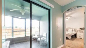 Ein Zimmer mit Glastür und Zugang zu einem Balkon mit Stühlen und Tisch.