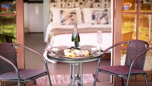 A dining table with a bottle and glasses, two chairs, and a view of a bedroom with a bed and pillows. - A Fantastic Location
"Just a short walk down the footpath opposite to the Beach" (Snells Beach)