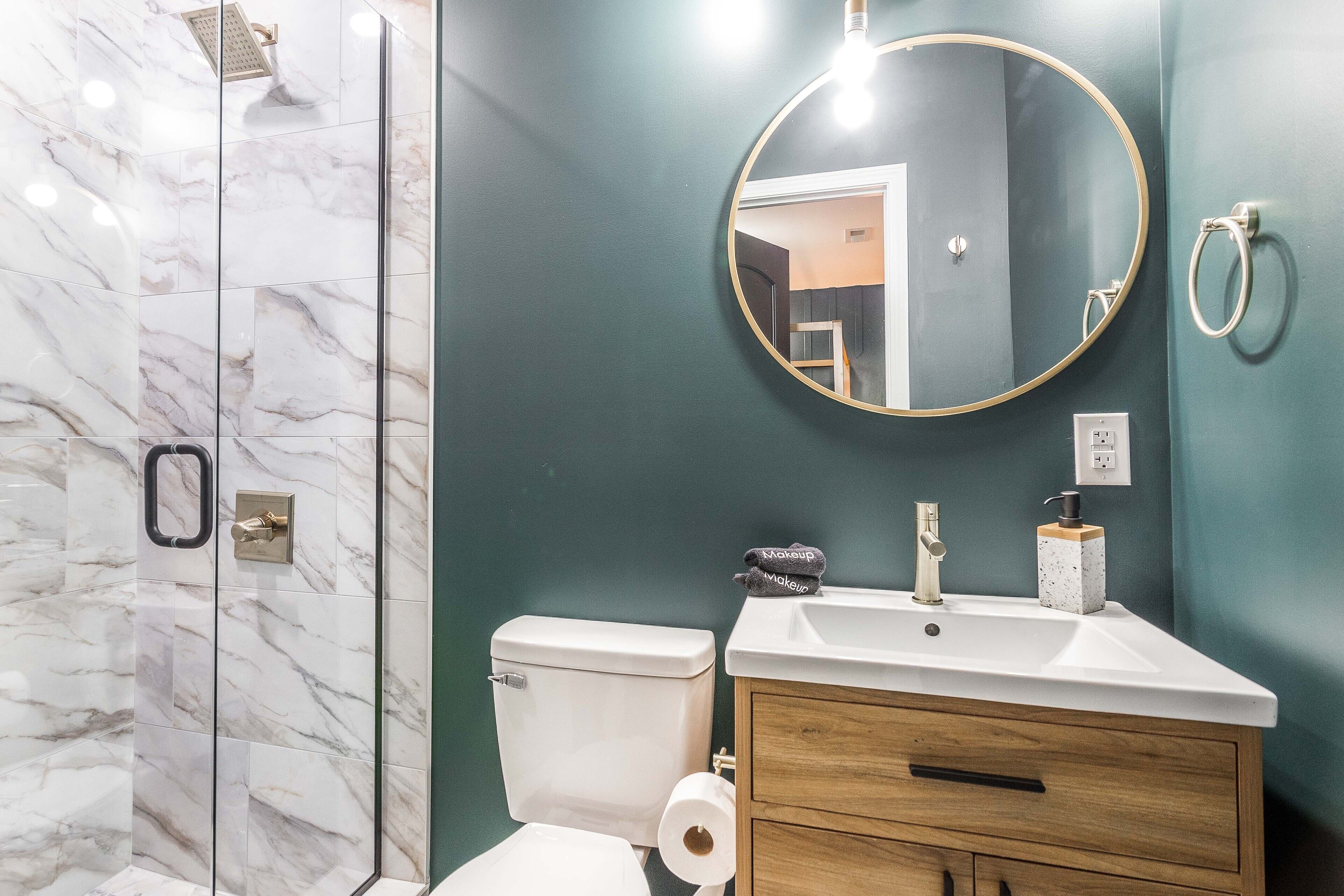 Un baño con ducha de mármol, inodoro, lavabo con espejo y tocador.