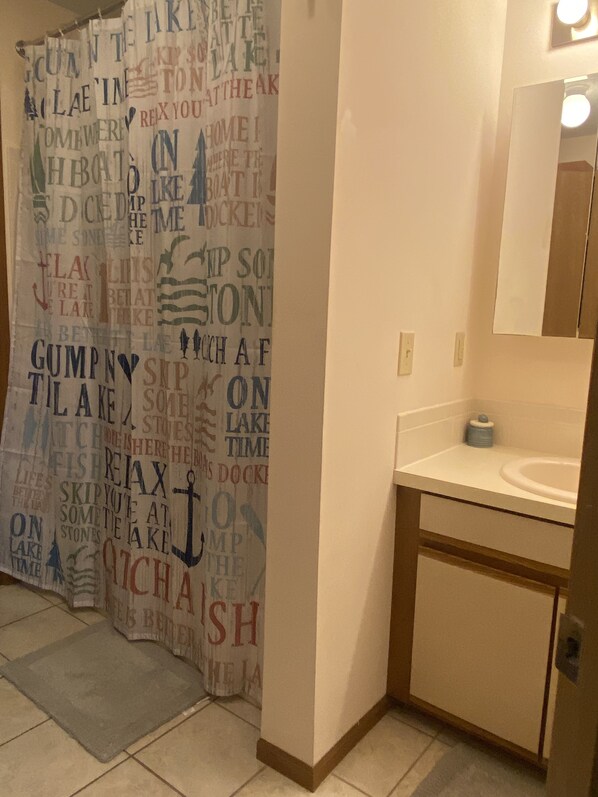 A bathroom with a shower curtain featuring nautical-themed text, a sink, and a mirror.