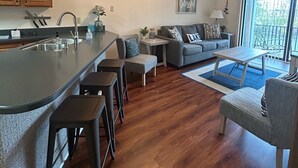 Une cuisine moderne dotée d’un îlot central, de tabourets de bar, d’une table à manger et d’un ventilateur de plafond.
