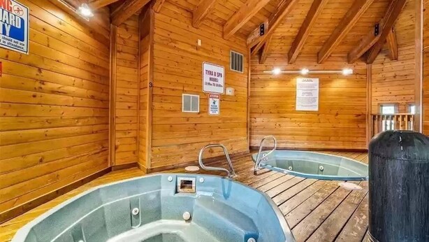 Un cuarto de spa de madera con dos jacuzzis, paredes de madera y un cartel que indica el nombre y el horario del spa.