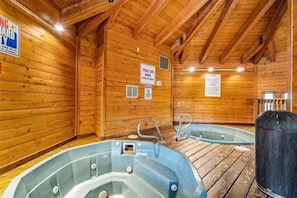 Una spa con una stanza in legno, due vasche idromassaggio, pareti in legno e un cartello con il nome e l'orario di apertura della spa.