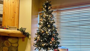 Una habitación acogedora con un árbol de Navidad, una pared de piedra y una cama con un cojín festivo.