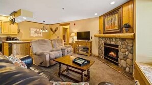 Una sala de estar con chimenea, dos sofás, una mesa de centro y un televisor.