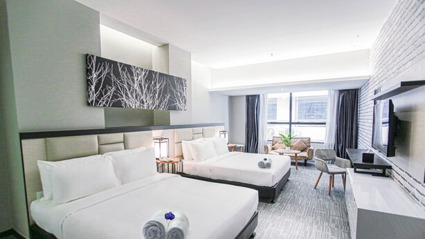 A hotel room with two beds, a desk, a TV, and a large window. - Fives Hotel DNP (Johor Bahru)