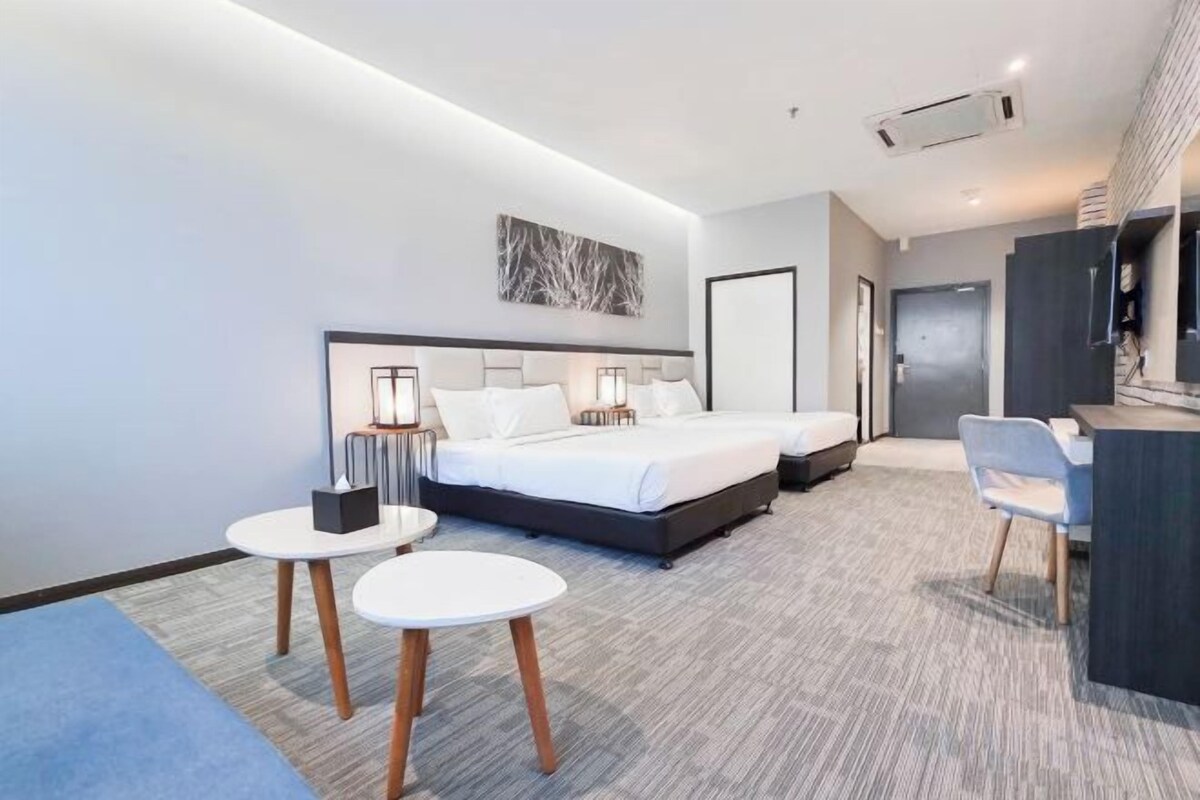 A modern hotel room with a large bed, two bedside tables, a desk, and a chair.