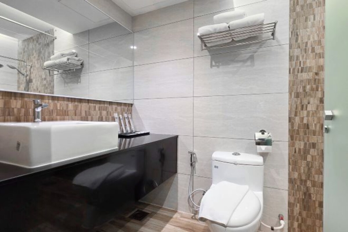 A modern bathroom with a large sink, toilet, and a mirror.