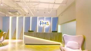 A reception area with a modern design, featuring a reception desk and two chairs. - Fives Hotel DNP (Johor Bahru)