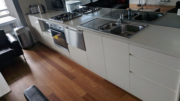 Una cocina moderna con armarios blancos, electrodomésticos de acero inoxidable y una isla grande con lavamanos.