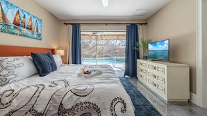 Un dormitorio con una cama grande, un televisor, un aparador y un cuadro de veleros.