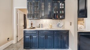 Una cocina con gabinetes azul oscuro, encimera de mármol y salpicadero.